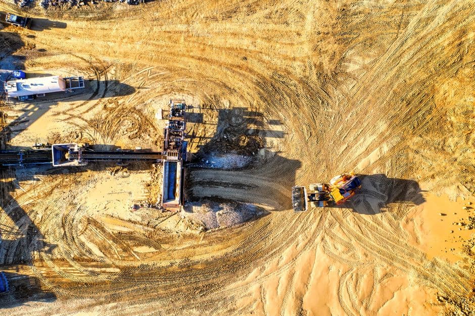 Aerial drone view of industrial construction site with heavy machinery.