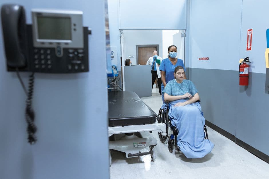 Nurse walking through a bright hospital corridor.